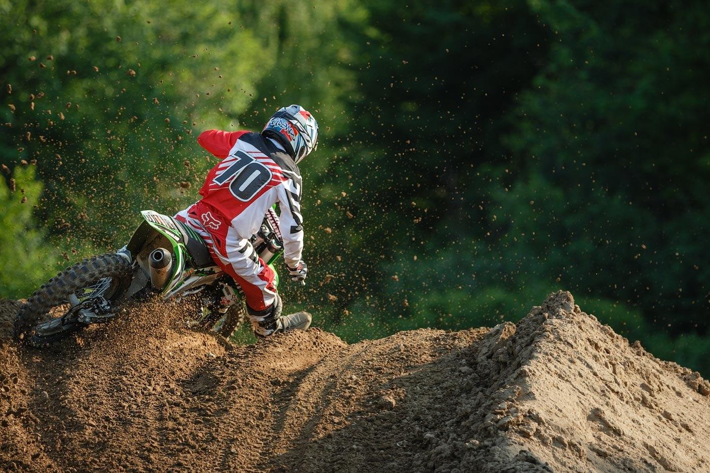 Rider #10 on a green bike throwing dirt off a berm